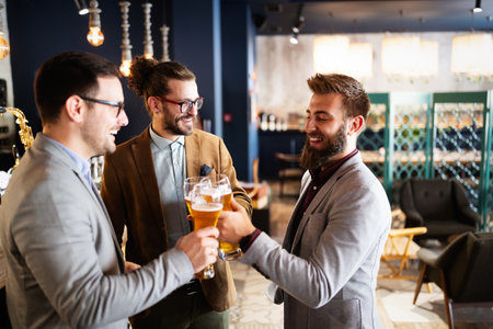 Business people drink beer after work in pub. Businessmen enjoy a beer.の写真素材