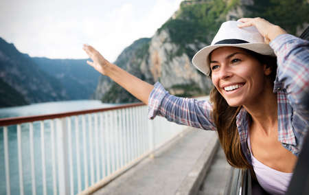 Woman in car road trip waving out the window smilingの写真素材