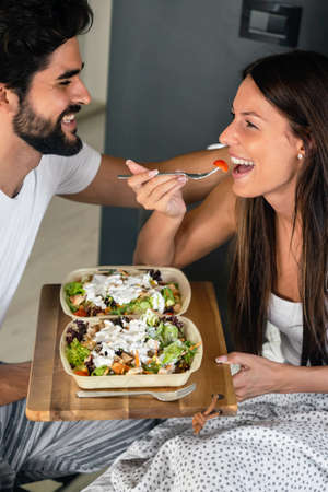 Hand holding breakfast tray to a happy relaxed woman in bedの写真素材