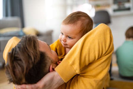 Happy young father playing with little daughter at home