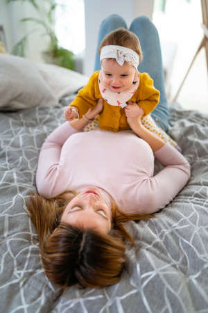 Young mother playing with her baby at homeの写真素材
