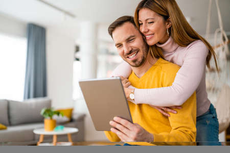 Happy couple spending time with tablet at homeの写真素材