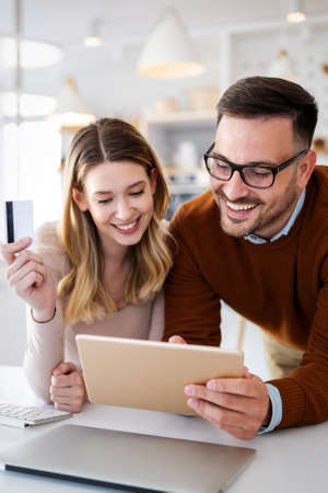 Happy smiling couple shopping online at home. Technology, e-commerce concept.の写真素材