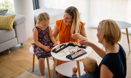 Women at the table playing board game with children. Family, nursery, childhood concept.