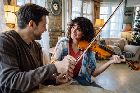 Violin teacher helping a woman student at homeの写真素材