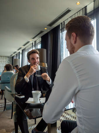 Coffee break. Two cheerful business men talking in a restaurantの写真素材