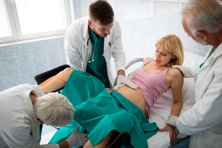 In the hospital woman in labor pushes to give birth, obstetricians assistingの写真素材