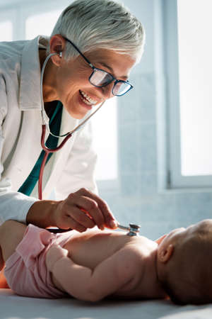 Pediatrician doctor examines baby with stethoscope checking heart beat.の写真素材