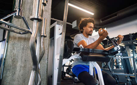 Confident fit young man exercising at fitness center.