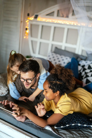 Multiethnic children and father having fun, playing on tablet at home