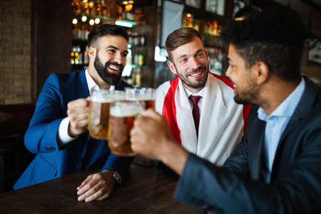 Men fans screaming and watching football on TV and drink beer in a pubの写真素材