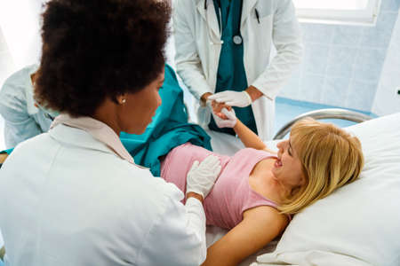 Pregnant woman pushes to give birth in hospital, obstetrician doctor assistingの写真素材