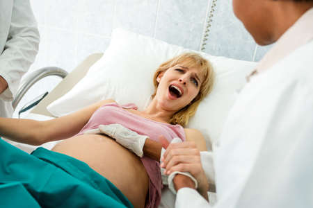 Pregnant woman pushes to give birth in hospital, obstetrician doctor assisting