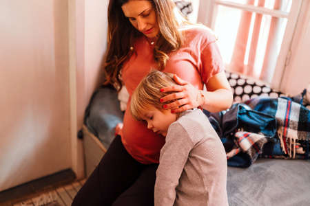 Happy child holding belly of pregnant woman. Family people love conceptの写真素材