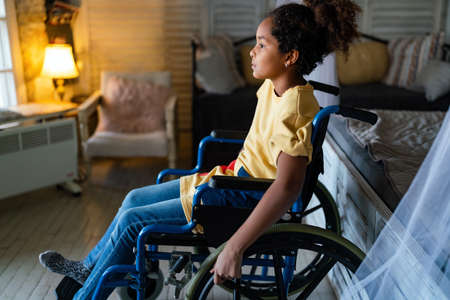 Portrait of disabled black girl with wheelchair at homeの写真素材