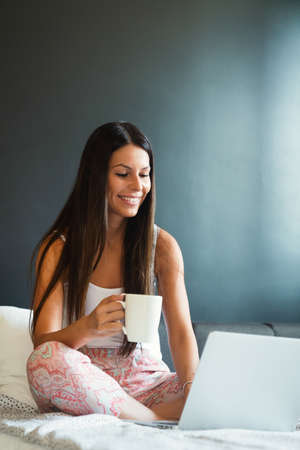 Beautiful woman working, studying with laptop on bed at home