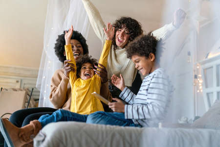 Family children gay parents concept. Happy multiethnic women couple having fun with kids at homeの写真素材