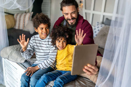 Multiethnic family happiness concept. Happy father and children using tablet and having fun at home