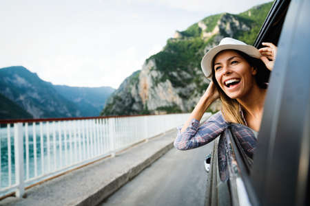 Woman in car road trip waving out the window smilingの写真素材
