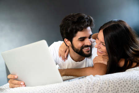 Happy young man and woman is having fun in bed together