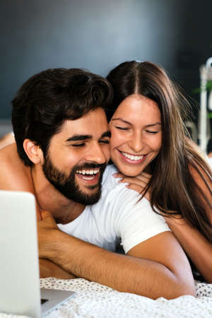 Young couple relaxing at home with laptop. Love, happiness, people and fun concept.の写真素材