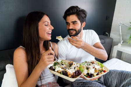 Romantic happy couple in love having breakfast in bedの写真素材