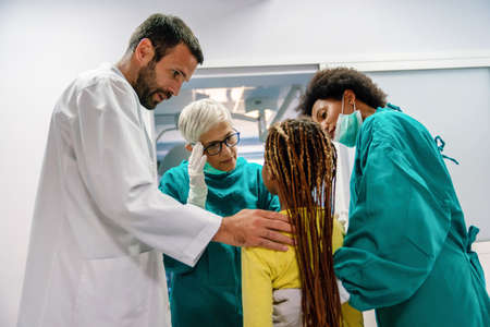 Group of doctor consoling little girl after bad news in hospital. Healthcare, doctor support conceptの写真素材