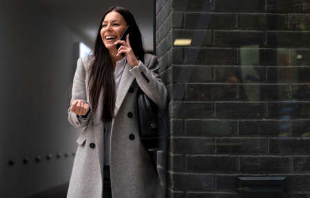 Successful businesswoman or entrepreneur using smartphone while walking outdoorの写真素材