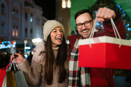 Happy couple having fun together on Christmas shopping. Holiday present people happiness concept