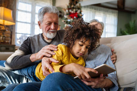 Portrait of happy grandparents with child playing together at homeの写真素材