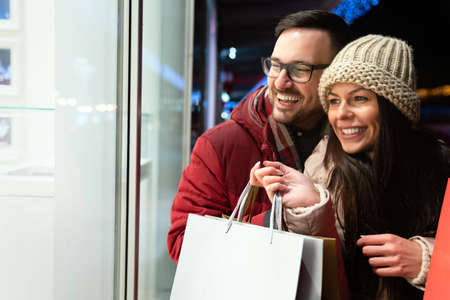 Beautiful young loving couple carrying bags and enjoying shopping together.の写真素材