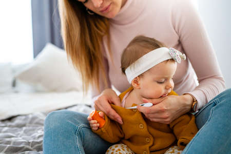 Mother checking temperature of her sick little daughter