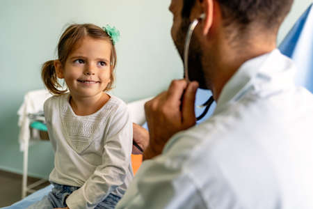 Doctor examining little girl with stethoscope in hospital. Healthcare, child, pediatrician concept.の写真素材
