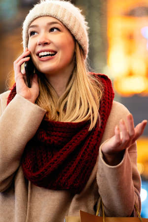 Portrait of smiling woman using mobile phone in the city at winter. People communication concept