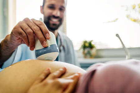 Obstetrician examining pregnant woman belly by ultrasonic scan in hospital, clinic.