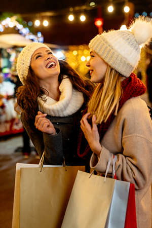 Portrait of happy women enjoying christmas shopping together in the cityの写真素材