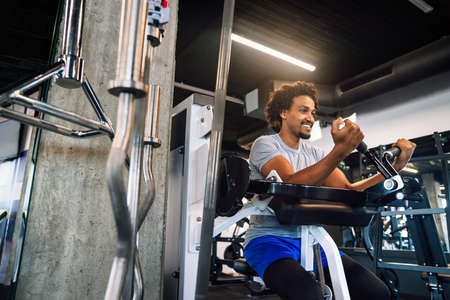 Young handsome man doing exercises in gym