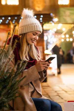 Festive christmas fair concept. Happy smiling woman having fun and shopping on the christmas market.の写真素材