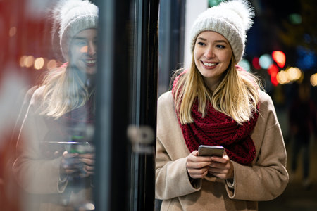 Young woman walking through town using a mobile phone smiling with pleasure