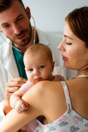 Pediatrician doctor medical examining little smiling baby, held by mother