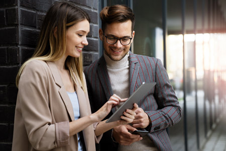 Successful young business people talking, working together in front of modern business buildingの写真素材