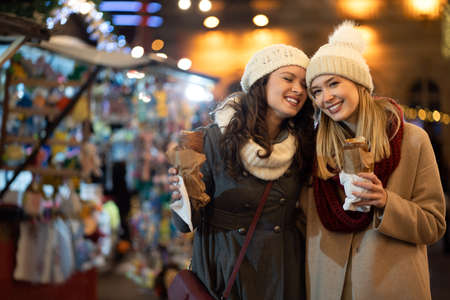 Festive christmas fair concept. Happy women having fun and shopping, enjoying on christmas market.の写真素材