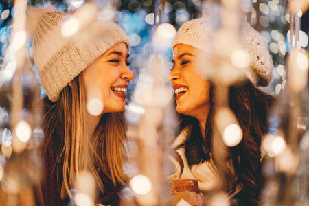 Happy women friends having fun, enjoying moments together in christmas decorated background.の写真素材