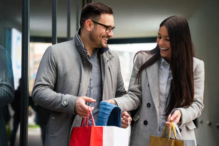 Beautiful young loving couple carrying bags and enjoying shopping together.