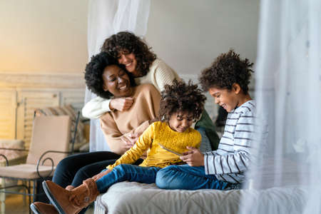 Happy lesbian multiethnic couple in love with childen at home. Family lgbt child happiness concept