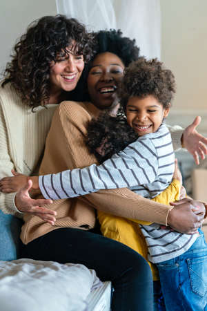 Family children gay parents concept. Happy multiethnic women couple having fun with kids at homeの写真素材