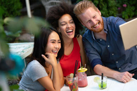 Friends having a great time in cafe, smiling and drinking cocktails enjoying together.