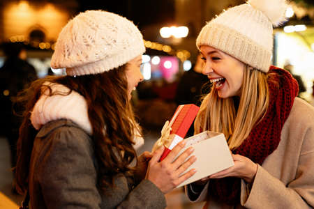 Portrait of happy women friends exchanging christmas present. Holiday people happiness conceptの写真素材