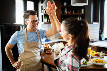 Portrait of happy young couple cooking together in the kitchen at home.の写真素材