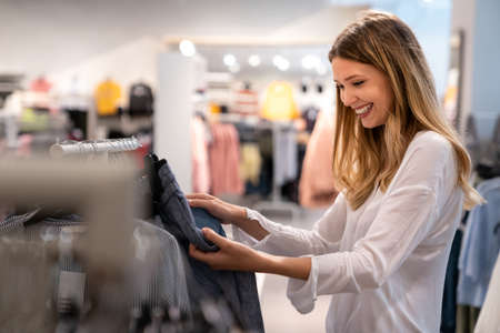 Happy young woman buying new clothes in store. Sale shopping fashion and people conceptの写真素材